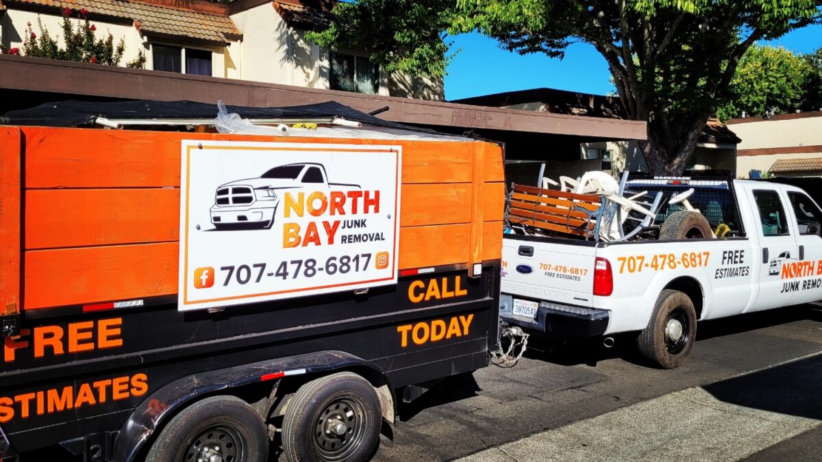 Orange and black trailer with North Bay Junk Removal logo outside house
