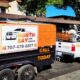 Orange and black trailer with North Bay Junk Removal logo outside house