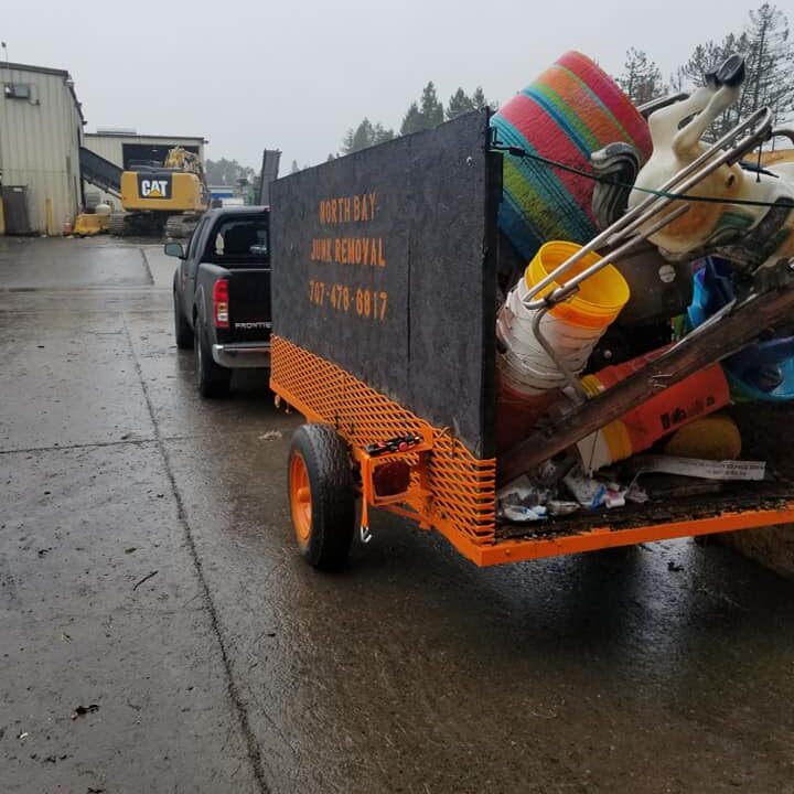 Grey and orange trailer attached to van carrying junk
