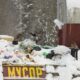 Pile of garbage in snow with birds flying nearby